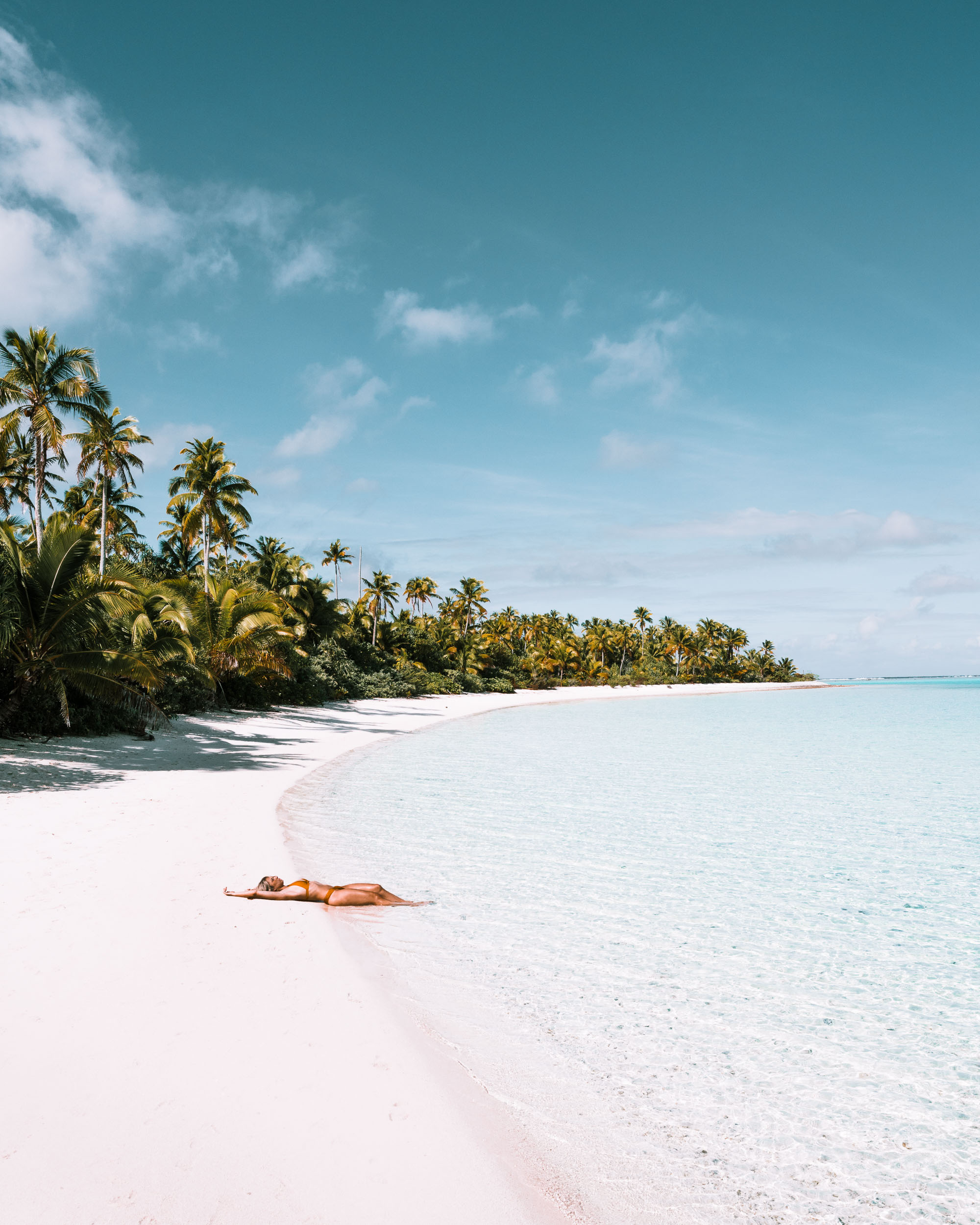 White sand beaches and palm trees and lying in the sand at One Foot Island in the Cook Islands